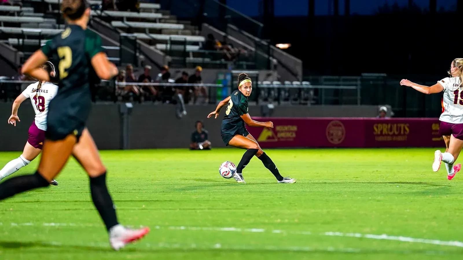 Jugadora pasa el balón en partido de fútbol femenino Jugadora pasa el balón en partido de fútbol femenino