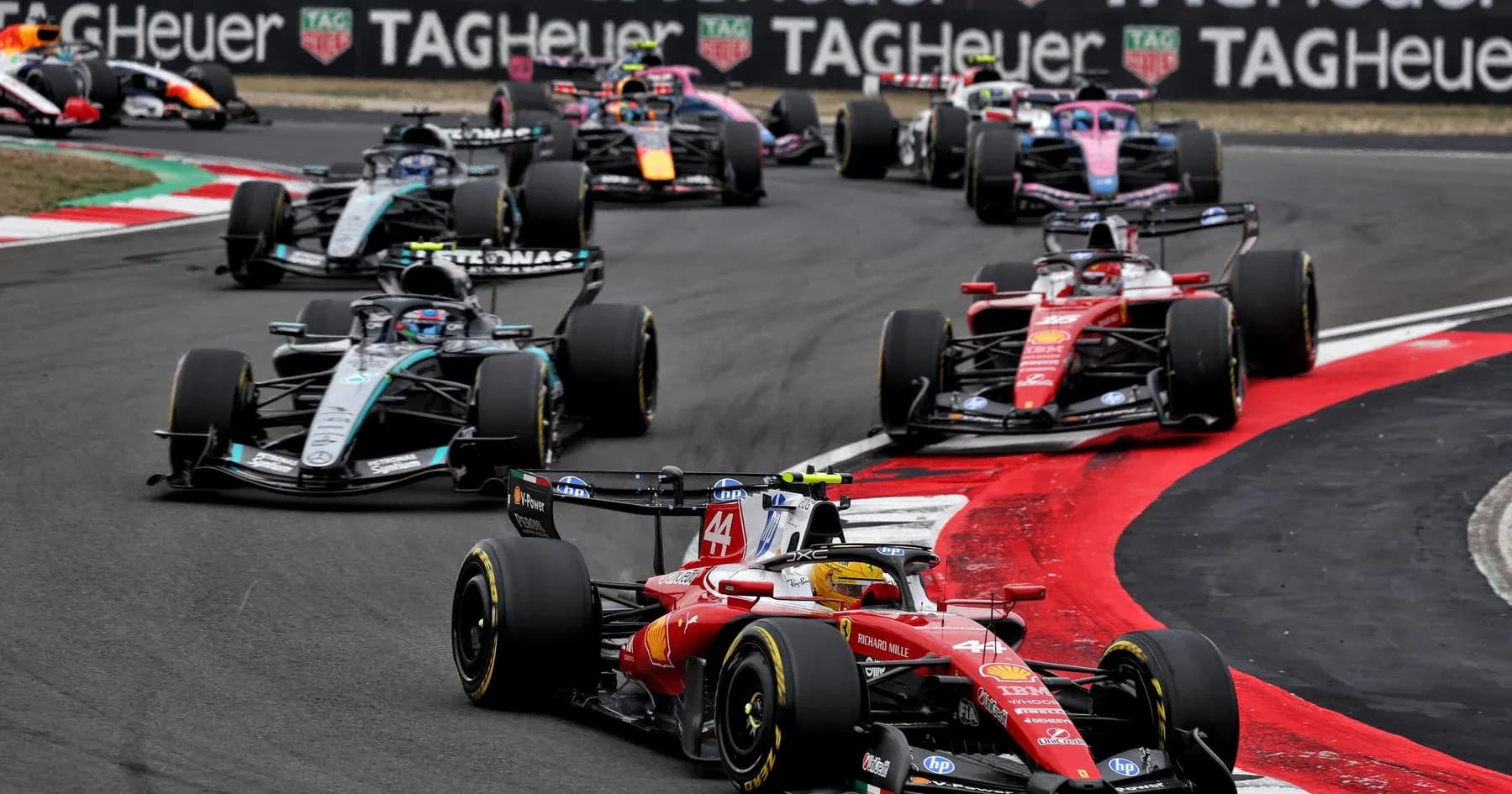 Varios coches de Fórmula 1 compitiendo en curva Varios coches de Fórmula 1 compitiendo en curva